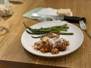 Meatballs and asparagus on a plate, with parmesan in the background