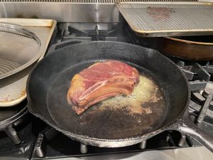 Ribeye cooking in a cast-iron pan