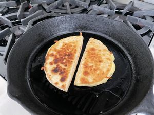 two quesadillas cooking in a cast-iron skillet