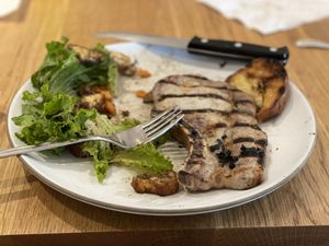 Pork chop with green salad and grilled bread
