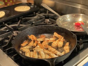 Fish frying while tortillas warm up in the background